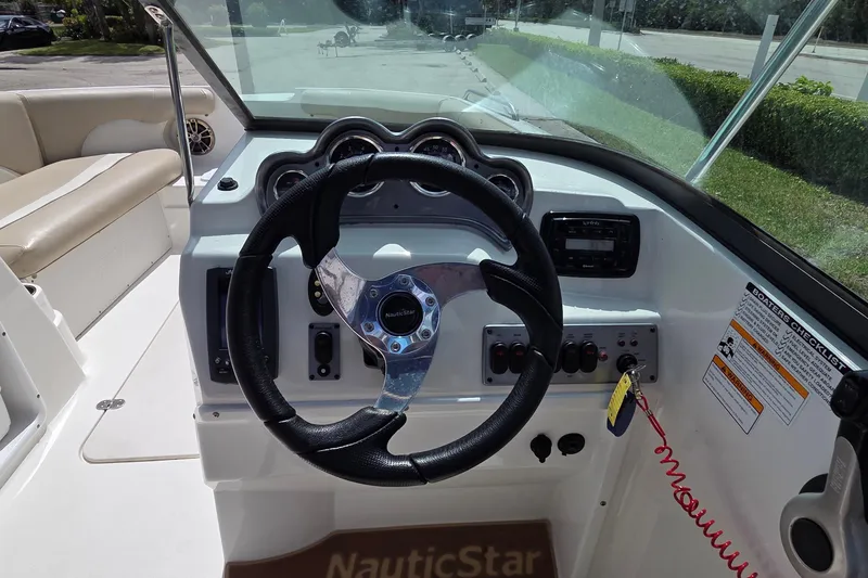 Slide: The Image of 2017 NauticStar 203DC Sport Deck boat dashboard with steering wheel and controls. - 8