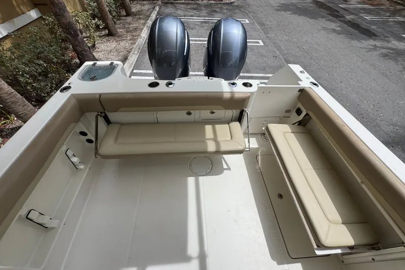 Slide: The Image of 2018 Sailfish 275 DC boat interior with beige seating and dual outboard motors. - 10