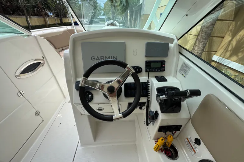 Slide: The Image of 2018 Sailfish 275 DC helm with Garmin navigation, steering wheel, and control panel. - 14