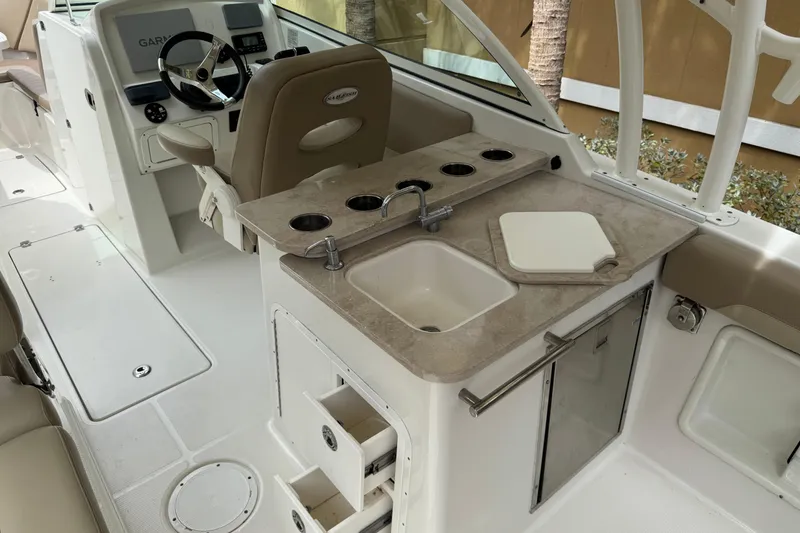 Slide: The Image of 2018 Sailfish 275 DC boat interior with helm, steering wheel, and sink area. - 22