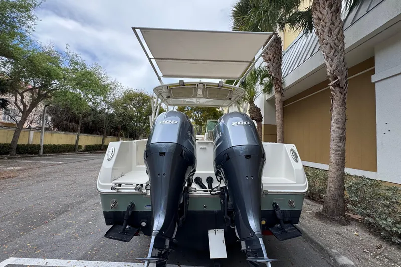 Slide: The Image of 2018 Sailfish 275 DC boat with dual Yamaha 200 engines, parked near palm trees. - 5