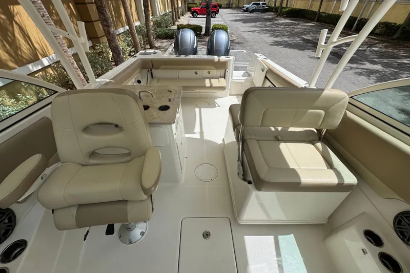 Slide: The Image of 2018 Sailfish 275 DC boat interior with beige seating and dual engines. - 7
