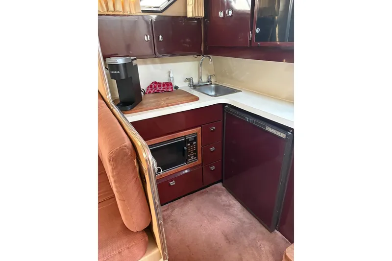 Slide: The Image of 1986 Wellcraft 3200 St. Tropez boat kitchen with sink, microwave, and fridge. - 10
