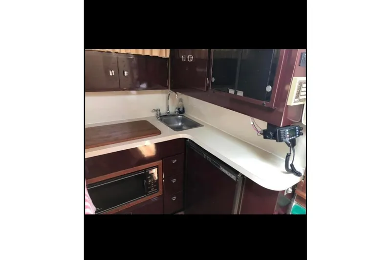Slide: The Image of 1986 Wellcraft 3200 St. Tropez boat kitchen with sink, microwave, and cabinetry. - 11