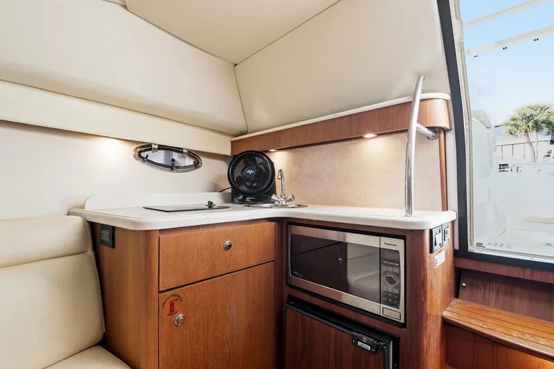 Slide: The Image of 2007 Tiara Yachts 3000 Open interior kitchen with sink, microwave, and wooden cabinetry. - 16