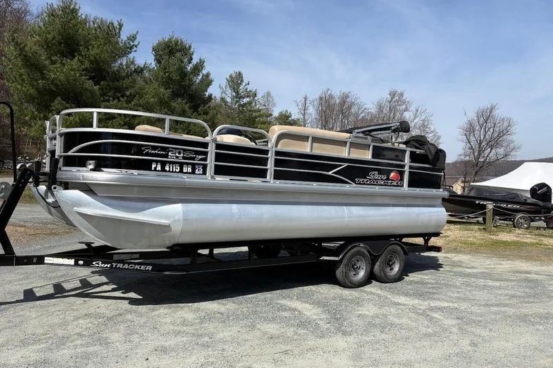The Image of 2016 Sun Tracker Fishin' Barge 20 DLX pontoon boat on trailer, parked outdoors. - 0