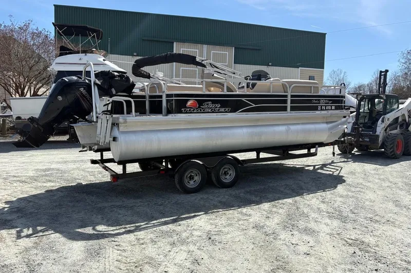 Slide: The Image of 2016 Sun Tracker Fishin' Barge 20 DLX pontoon boat on trailer in outdoor setting. - 2