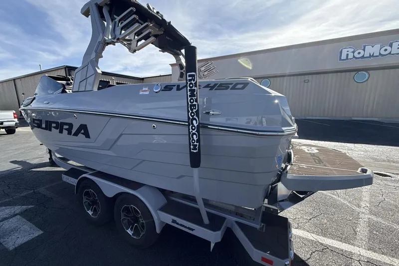 Slide: The Image of 2024 Supra SV boat on trailer, parked outdoors under clear sky. - 3