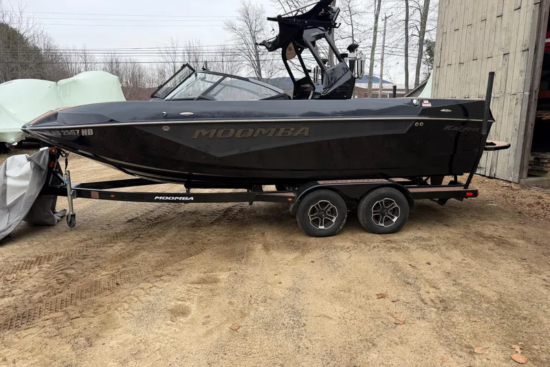 Slide: The Image of 2022 Moomba Kaiyen boat on trailer, parked outdoors near a wooden structure. - 23