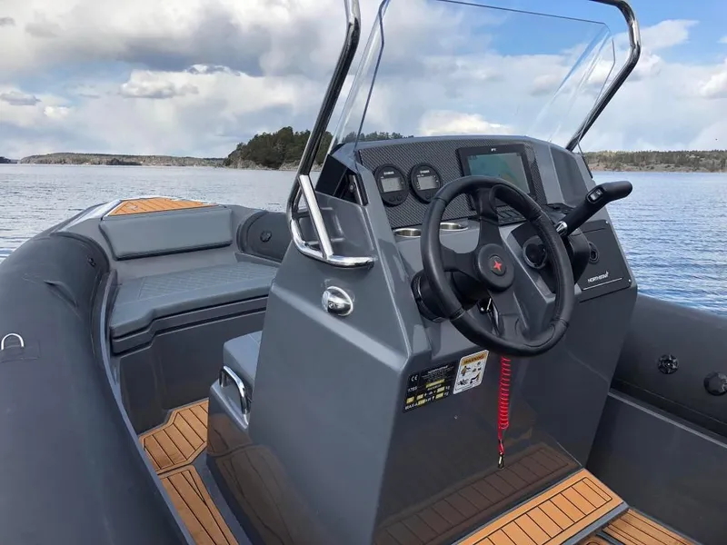 Slide: The Image of 2024 Northstar Orion 6 boat dashboard with steering wheel and controls on a calm lake. - 7