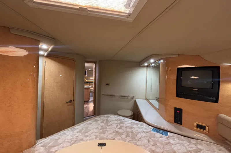 Slide: The Image of Interior of 1998 Sea Ray 500 Sundancer yacht with bed, TV, and wooden accents. - 19