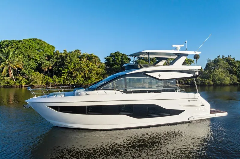 Slide: The Image of 2026 Cruisers Yachts 50 Fly on serene water with lush greenery backdrop. - 33