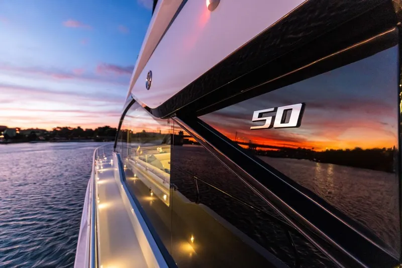 Slide: The Image of 2026 Cruisers Yachts 50 Fly at sunset, reflecting vibrant sky on water. - 87