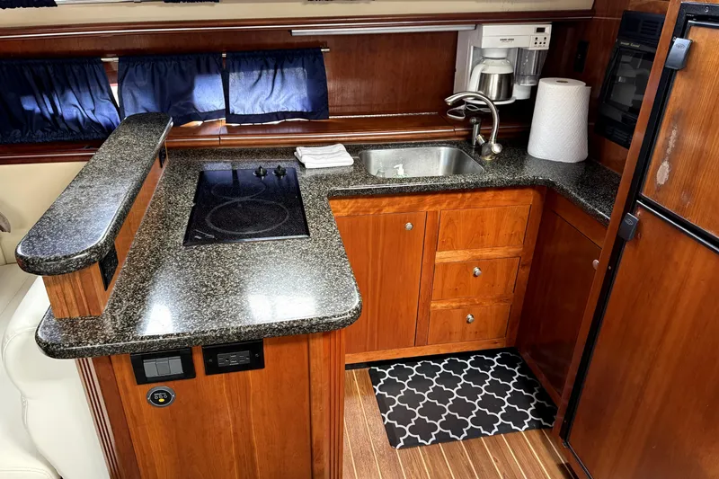 Slide: The Image of Luxurious 2005 Cruisers Yachts 405 Express Motoryacht kitchen with granite countertops and wooden cabinetry. - 13