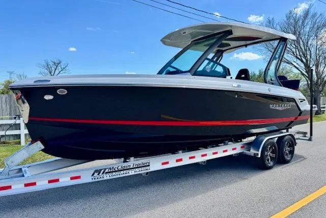 The Image of 2026 Monterey Elite 25 OB boat on trailer, sleek black design, parked on road. - 1