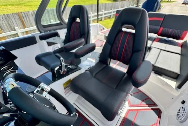 Slide: The Image of 2026 Monterey Elite 25 OB boat interior with black and red seating and steering wheel. - 14