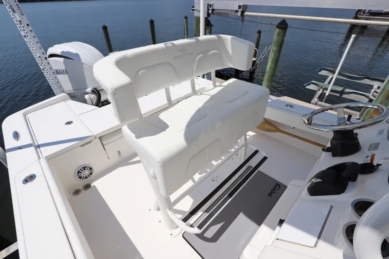 Slide: The Image of 2021 Regulator 24XO boat interior with white seating and steering wheel by the dock. - 16