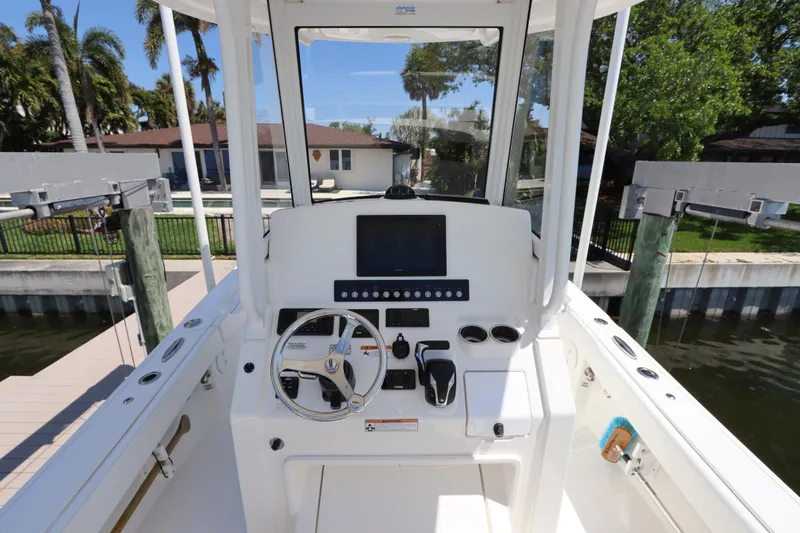 Slide: The Image of 2021 Regulator 24XO boat helm with steering wheel and control panel, docked near waterfront homes. - 17