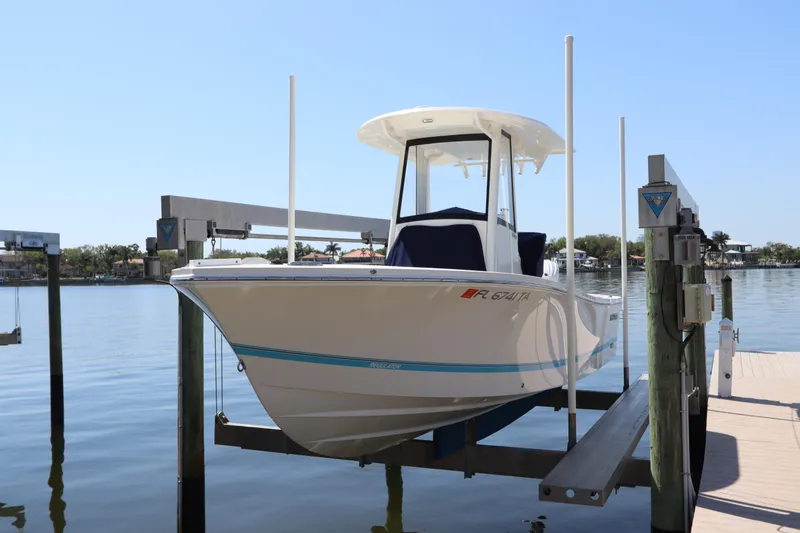 Slide: The Image of 2021 Regulator 24XO boat on lift, docked by calm waters under clear blue sky. - 2
