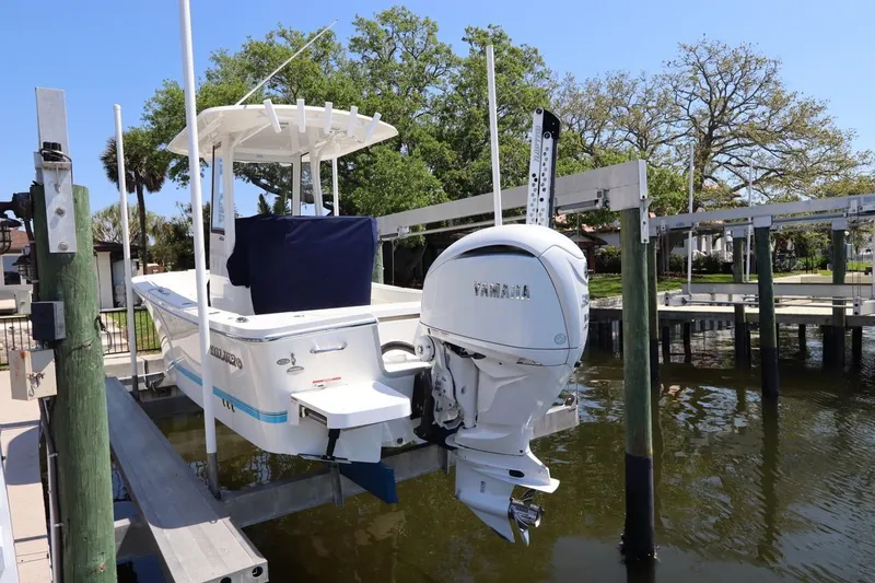 Slide: The Image of 2021 Regulator 24XO boat with Yamaha engine on a lift by the water. - 3