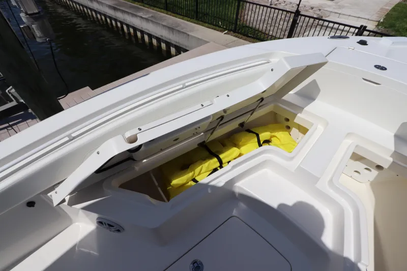 Slide: The Image of Open storage compartment on 2021 Regulator 24XO boat, revealing yellow life jackets. - 31