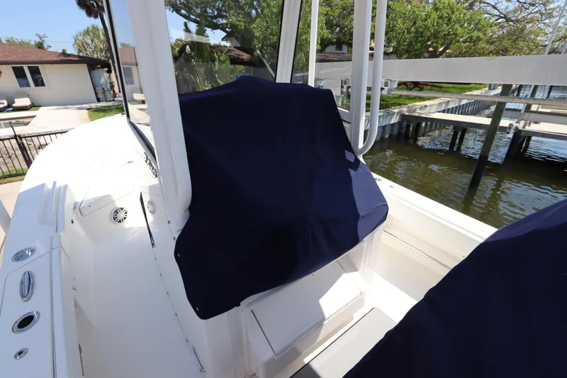 Slide: The Image of 2021 Regulator 24XO boat interior with covered seating, docked by a waterfront home. - 42