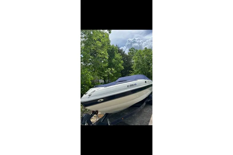 Slide: The Image of 2007 Bryant 270 boat on trailer, surrounded by trees under a cloudy sky. - 29