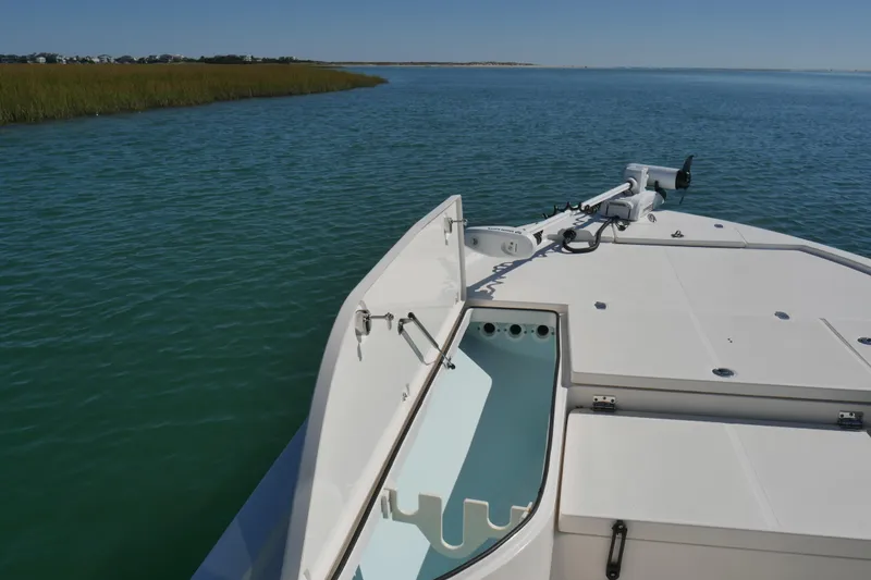 Slide: The Image of 2023 Sea Born FX24 Bay boat on calm water, featuring open storage and trolling motor. - 8