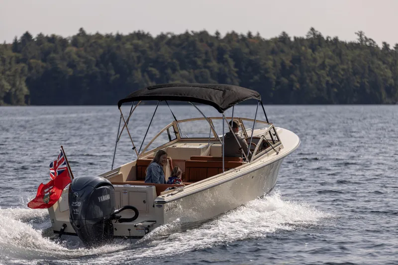 Slide: The Image of 2026 Rossiter 23 boat cruising on a lake with passengers, featuring a Yamaha engine. - 2