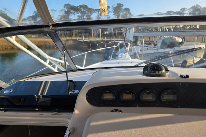 Slide: The Image of 2004 Grady-White Express 330 boat dashboard with gauges and compass, docked near a marina. - 22