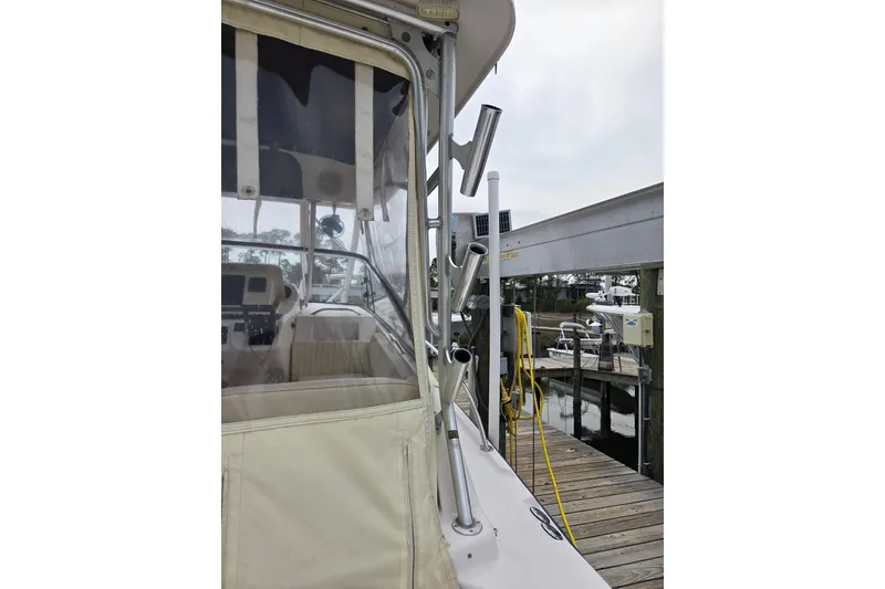 Slide: The Image of 2004 Grady-White Express 330 boat docked, showcasing cockpit and fishing rod holders. - 36