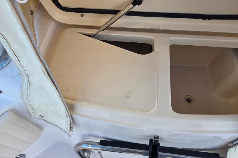 Slide: The Image of Storage compartment on a 2004 Grady-White Express 330 boat, featuring a hinged lid and drainage hole. - 43