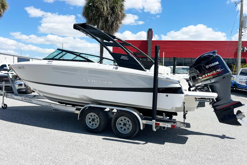 Slide: The Image of 2022 Regal LX2 boat on trailer with Yamaha outboard motor, parked outdoors. - 13