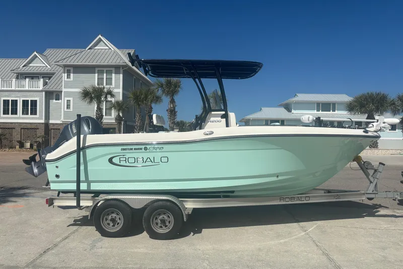 The Image of 2023 Robalo R200 Center Console boat on trailer, parked near coastal homes. - 0
