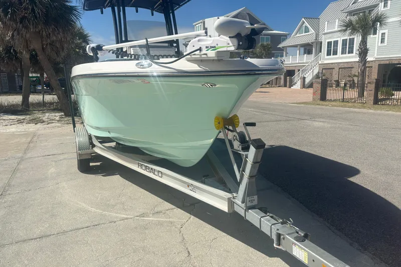 Slide: The Image of 2023 Robalo R200 Center Console boat on trailer, parked near coastal homes. - 2