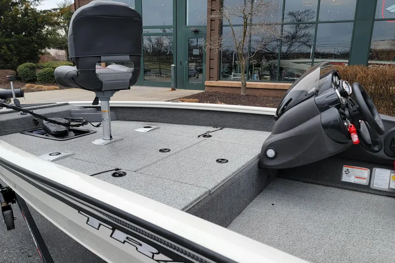 Slide: The Image of 2024 Tracker Pro Team 175 TF boat with seating and control panel, parked outdoors. - 5