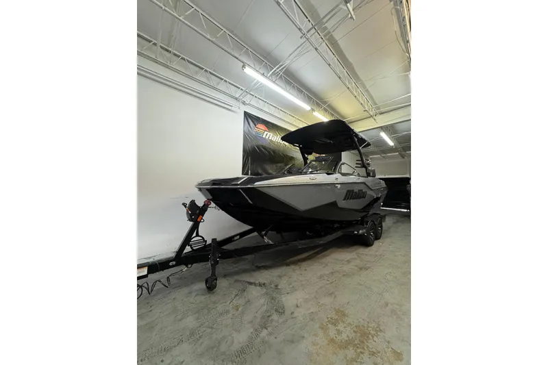The Image of 2026 Malibu M230 boat in showroom, sleek design, black and gray color scheme. - 0