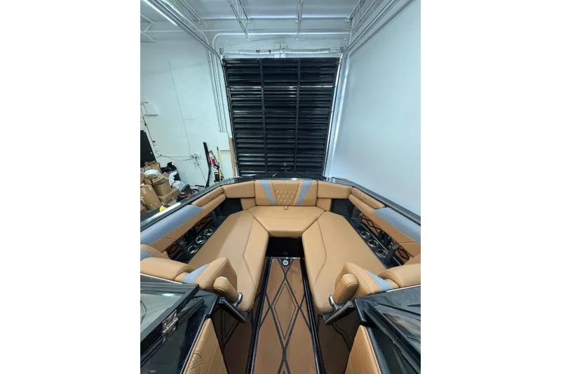 Slide: The Image of 2026 Malibu M230 boat interior with tan leather seating in a showroom. - 6