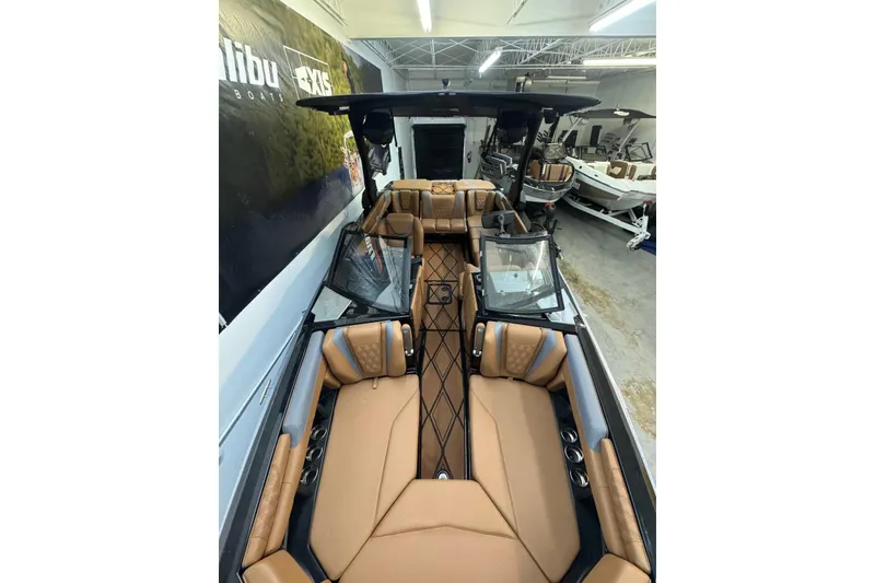 Slide: The Image of 2026 Malibu M230 boat interior with tan leather seating and sleek design in showroom. - 8
