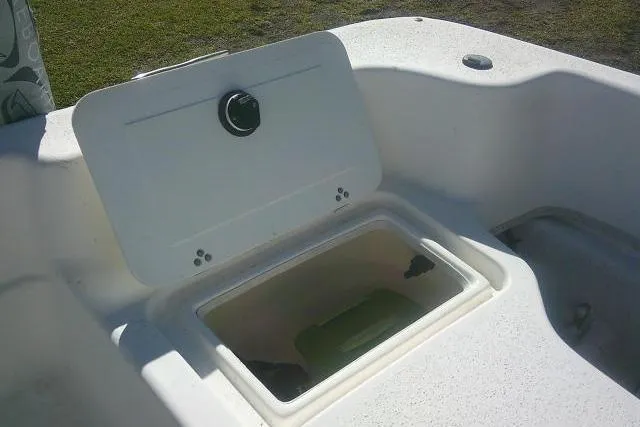 Slide: The Image of 2011 Carolina Skiff 258 DLV boat storage compartment with open lid, showcasing interior space. - 24