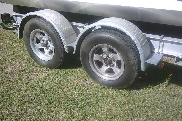 Slide: The Image of Trailer wheels for 2011 Carolina Skiff 258 DLV boat on grass. - 6