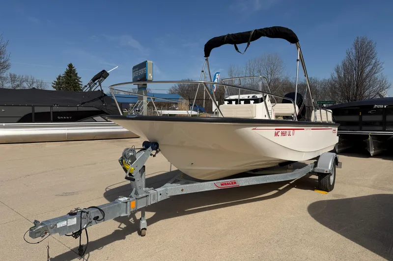 Slide: The Image of 2020 Boston Whaler 170 Montauk boat on trailer, parked outdoors under clear sky. - 2