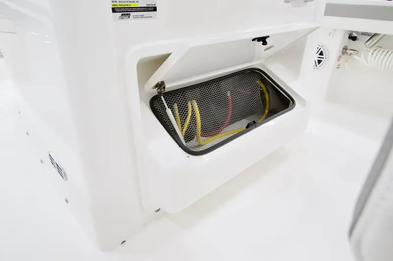 Slide: The Image of 2026 Regulator 23 boat storage compartment with mesh cover and visible wiring. - 11
