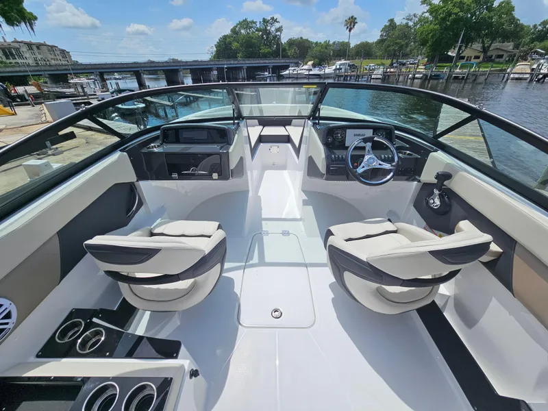 Slide: The Image of 2025 Monterey M-225 boat interior with modern seating and steering, docked by a scenic waterfront. - 12