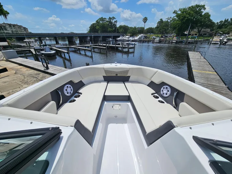 Slide: The Image of 2025 Monterey M-225 boat interior with spacious seating, docked at a scenic marina. - 19