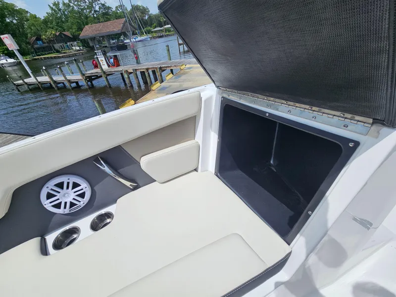 Slide: The Image of 2025 Monterey M-225 boat interior with open storage compartment and speaker, dockside view. - 22