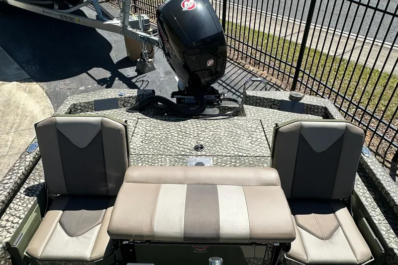 Slide: The Image of 2026 Vexus ACX 2000 boat interior with seating and motor, parked near a fence. - 12