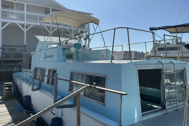 Slide: The Image of 1972 Whitcraft Hatteras boat docked, featuring light blue exterior and upper deck canopy. - 14