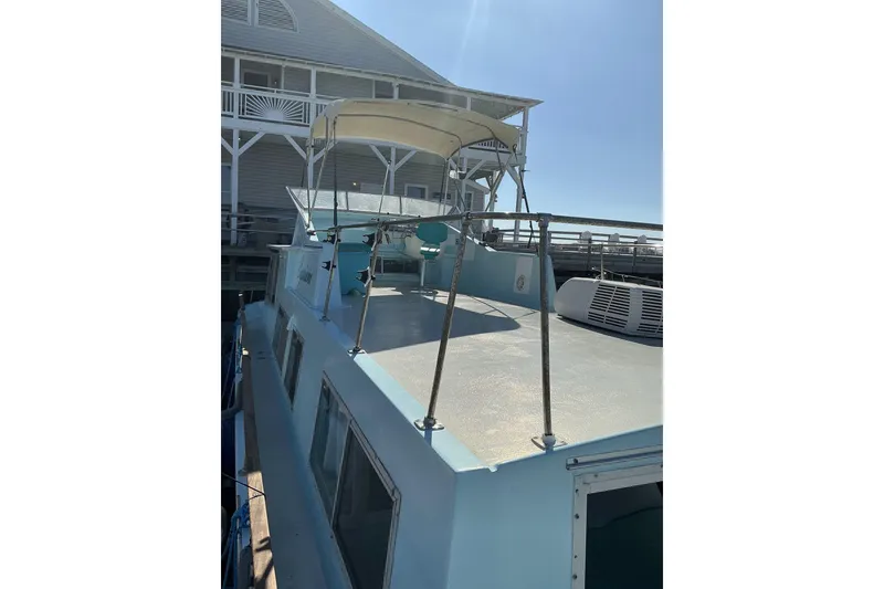 Slide: The Image of 1972 Whitcraft Hatteras boat docked near a wooden building under clear blue sky. - 15