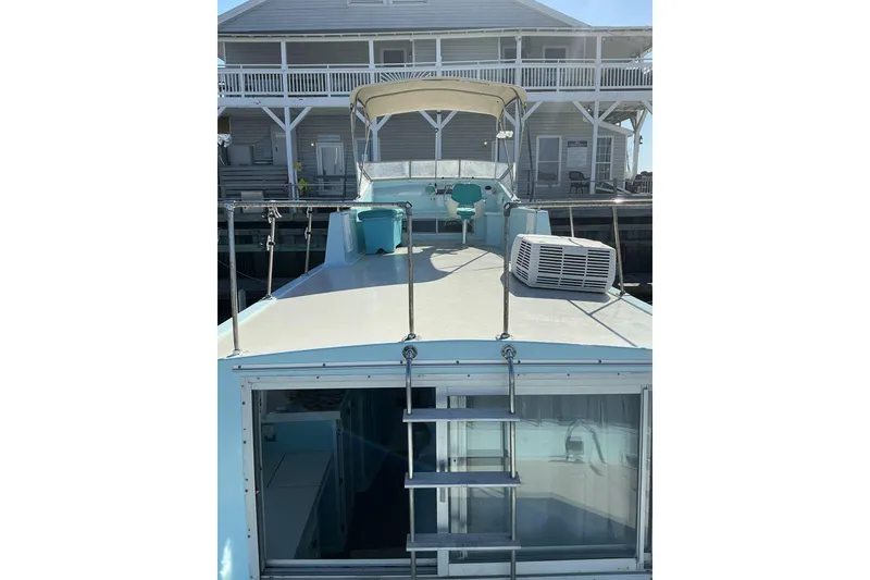 Slide: The Image of 1972 Whitcraft Hatteras boat with upper deck and ladder, docked near a building. - 16